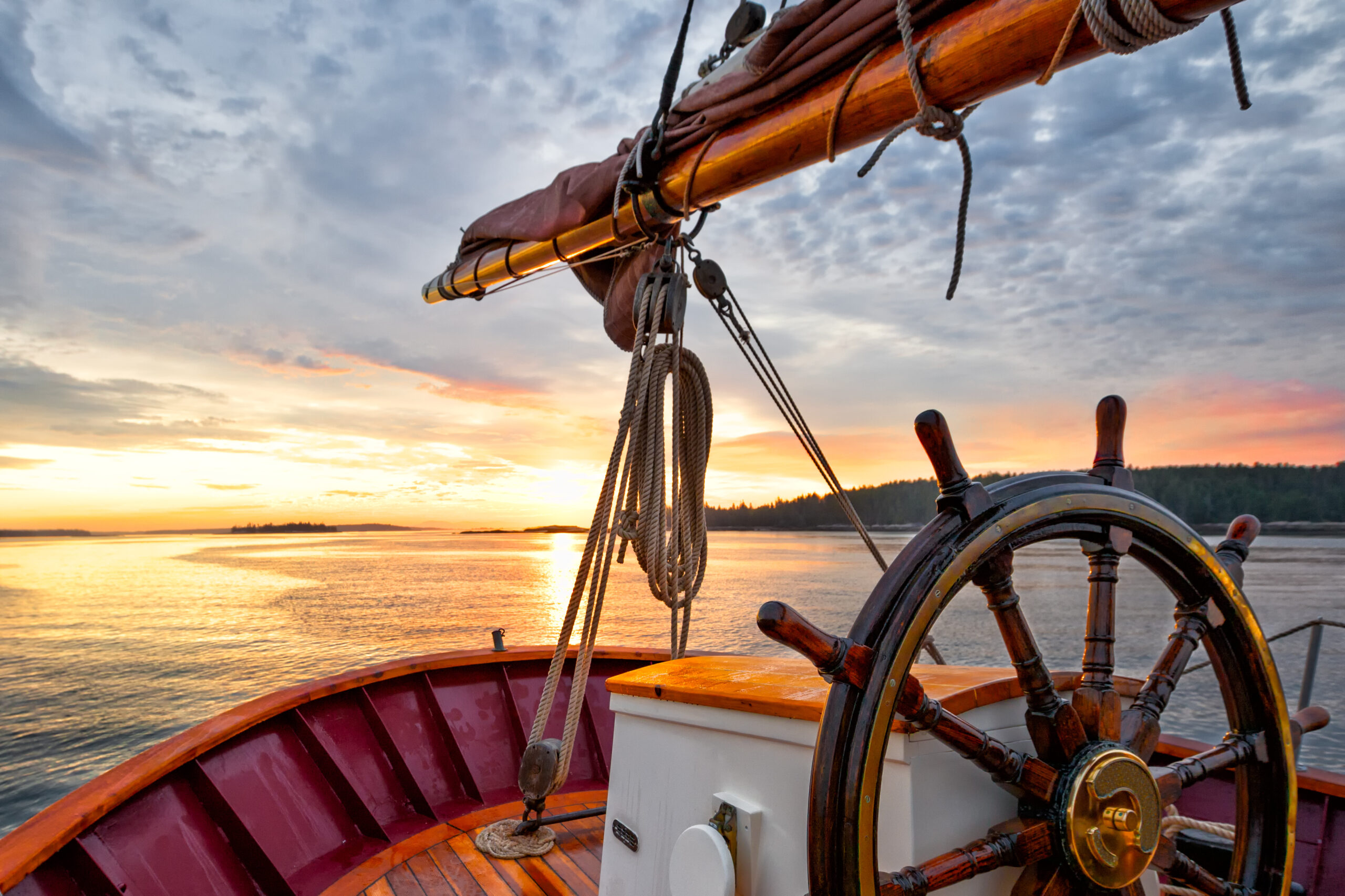 Sunrise sailing on a tall ship schooner. Close up of steering w